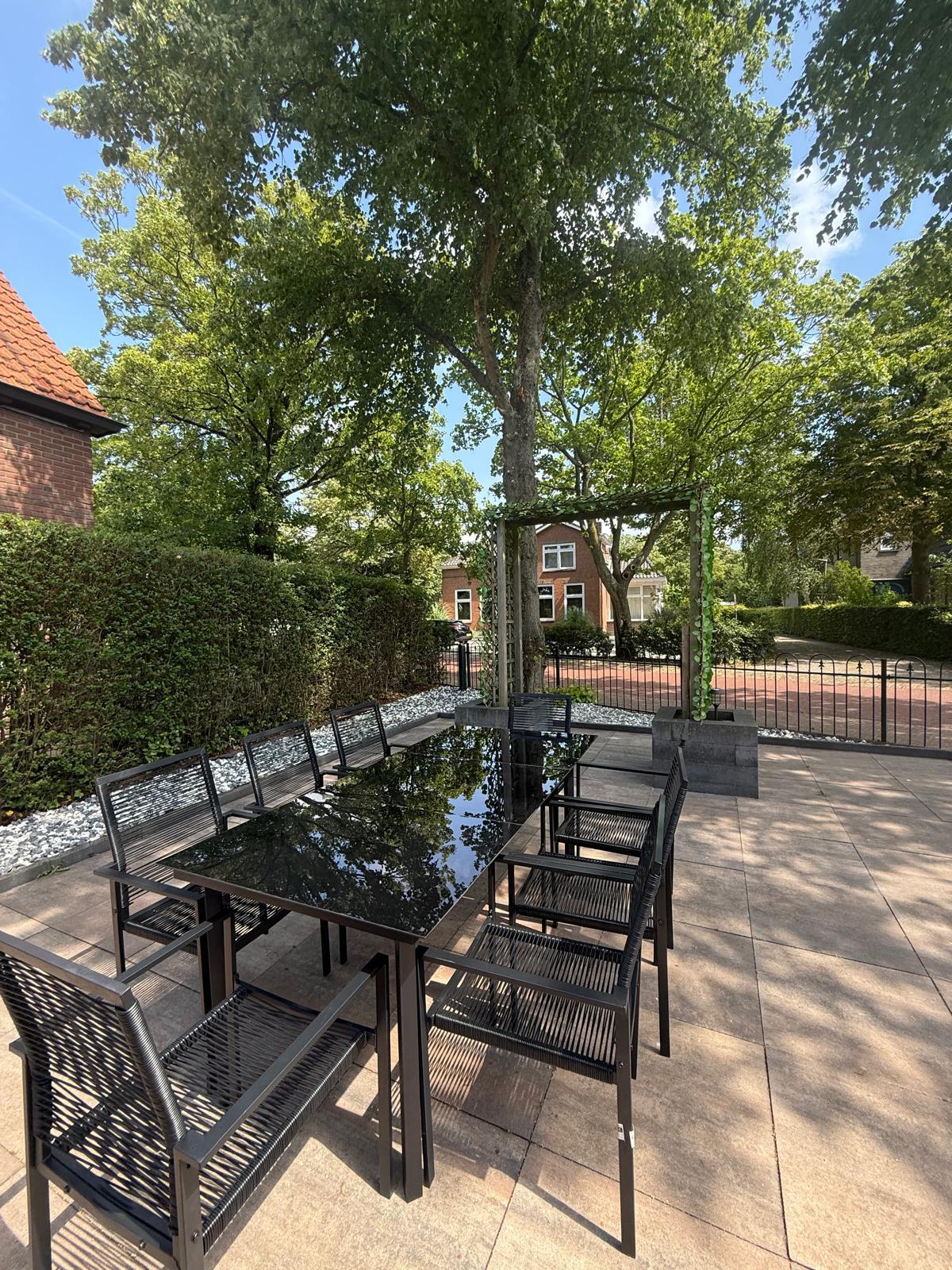 Zonnig terras met grote tafel onder de bomen